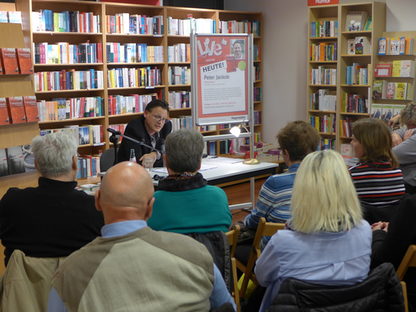 Autor liest ein Buch, davor sitzt das Publikum