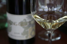Ein Glas mit Weißwein und eine Flasche Weißwein im Hintergrund